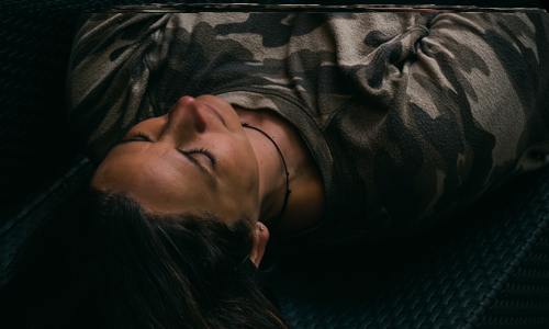 Woman wearing camouflage top lying down with eyes closed