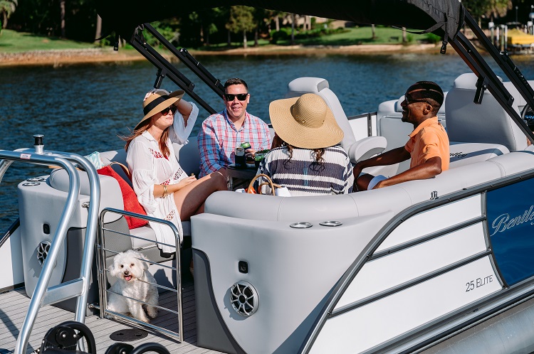 A family is boating in a Bentley® pontoon boat on a lake.