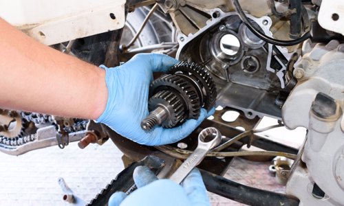 A person repairing a gear of an ATV