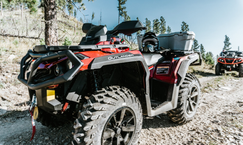 Two Can-Am® ATVs on a dirt road in the mountain.