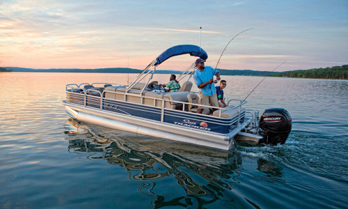 Three men are boating and fishing a SUN TRACKER® pontoon boat on a lake.