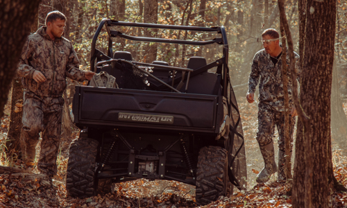 Two men are preparing to hunt near an Intimidator® UTV in the forest.