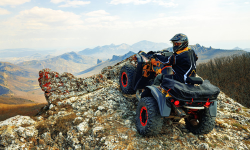 A man rides an ATV on the mountain.