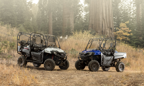 Two Honda® UTVs parked on the ground in the forest