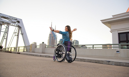 A happy woman on her manual wheelchair on a bridge 