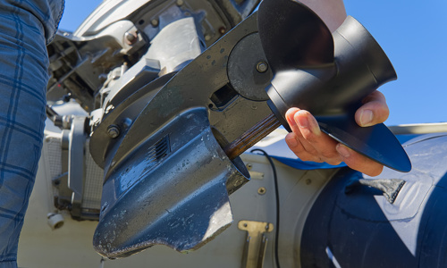 Close-up of a man changing propeller on an outboard motor.
