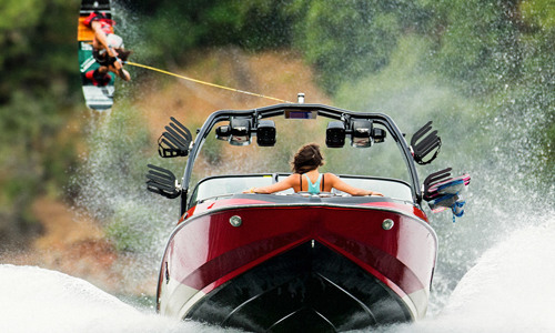 Some guys are doing wake surfing in a Centurion® boat on a lake.