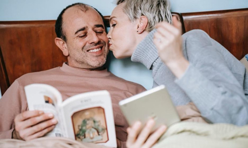 Woman kissing man holding a book